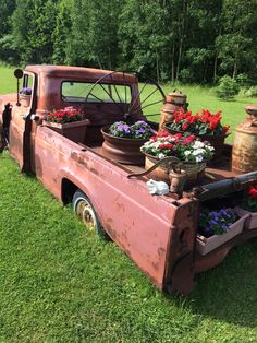 an old pick up truck with flowers in the bed and potted plants on the back