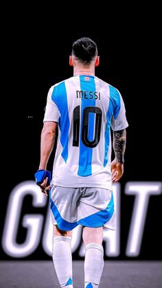 a soccer player with tattoos on his arms and legs walks down the field in front of a sign that reads messi 10