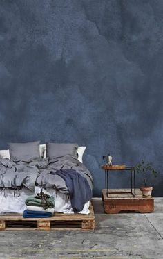 a bed sitting on top of a wooden pallet in front of a blue wall