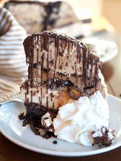 a piece of cake on a plate with whipped cream and chocolate drizzle