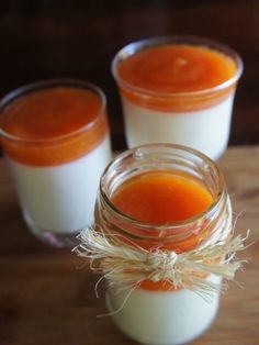 three jars filled with orange liquid sitting on top of a wooden table