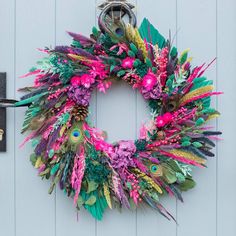 a colorful wreath hanging on the side of a white door next to a mailbox