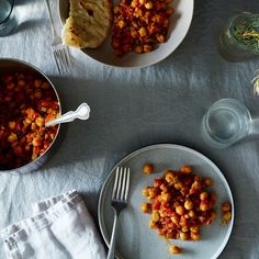 a table topped with two bowls filled with food next to silverware and utensils