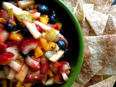 a bowl filled with fruit and chips on top of a table next to some tortilla chips