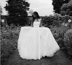 a woman in a white dress is walking through some bushes