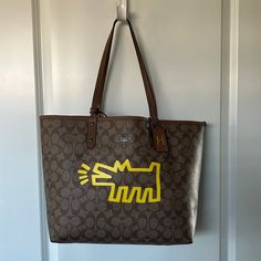 Limited Edition Collection Classic Coach Tote Bag W/ Iconic Keith Haring Barking Dog Graphic Removable Wristlet/Pouch W/ Top Zipper Brown Coated Canvas W/Coach Logo & Brilliant Fellow Graphic Reverses To Plain Brown Inside Logo Tag Approx 17” (Width At Top) X 12” X 6” Almost New Condition W/Hardly Any Use. Slight Wear/Scuffs On Bottom Corners, Mainly Front Ones (Illustrated In Pics). A Good Cobbler Might Be Able To Repair Or Treat To Cover/Protect Coach Tote Bag, Barking Dog, Wristlet Pouch, Coach Tote Bags, Coach Logo, Coach Tote, Logo Tag, Keith Haring, Brown Coat