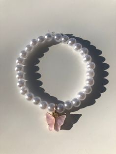 White pearl bracelet with a pink butterfly Beads Breclate Ideas, White Bead Bracelet Ideas, Charms For Bracelet, Diy Bracelets Design, Bracelet With Beads Ideas, Bracelet From Beads, Idea For Bracelet, Cute Pearl Bracelet Ideas, Pearl Bracelets Ideas