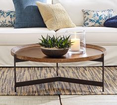 a living room with a white couch, coffee table and plants on the side tables