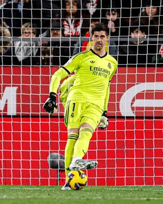 a soccer player is kicking the ball in front of an open goalie's net