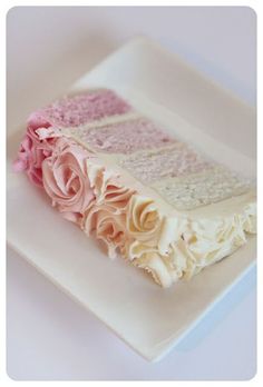 a white plate topped with a cake covered in pink and white frosted flowers on top of a table