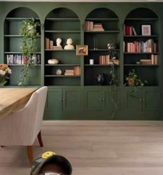 a dining room with green walls and built in bookshelves