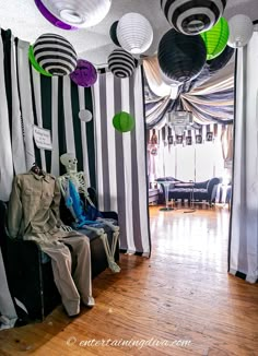 a room decorated for halloween with black and white striped walls, paper lanterns hanging from the ceiling