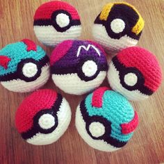 six crocheted pokeballs sitting on top of a wooden table