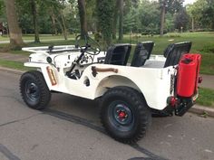 an old white jeep is parked on the side of the road