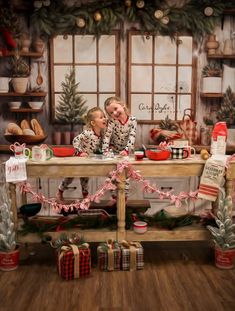 two children sitting at a table with christmas decorations