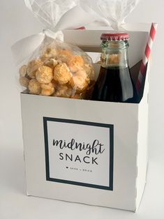 a bottle of soda and some snacks in a white box with a red striped straw