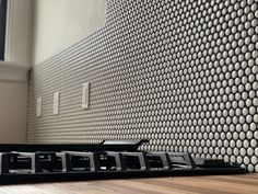 the back end of a computer keyboard on a wooden table in front of a wall