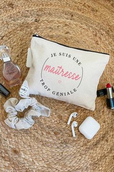 the contents of a personal care bag laid out on top of a straw mat, including an earbud, nail polish and lipstick