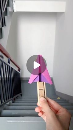 someone holding up a paper bird in front of some stairs