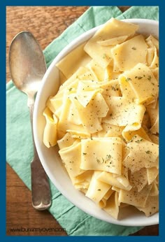 a white bowl filled with pasta on top of a green napkin