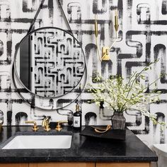 a bathroom with black and white wallpaper, gold fixtures and a mirror over the sink