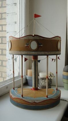 a carousel is sitting in front of a window with flags on the top and sides