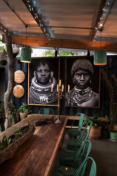 a long wooden table with green chairs and pictures on the wall