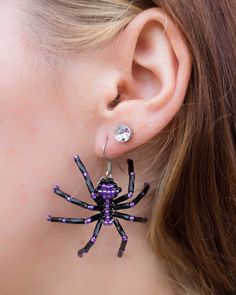 a close up of a person wearing spider earrings