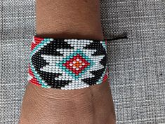 This exquisite handmade bracelet is crafted by skilled South American native artisans. Measuring 9 cm (3.5 inches) in width and 3 cm (1.2 inches) in height, it features vibrant beadwork in traditional geometric patterns. The combination of red, brown, black, white, and yellow beads reflects cultural symbols and heritage. Designed with an adjustable closure, this bracelet can comfortably fit larger wrists, making it both versatile and stylish. Each bead is placed with care, resulting in a durable, wearable piece of art that connects you to the rich traditions of indigenous craftsmanship. Check out more bracelets here  https://www.etsy.com/your/shops/me/tools/listings/section:28287253  #HandmadeJewelry #AdjustableBracelet #NativeArtisans #BeadedBracelet #IndigenousCrafts #SouthAmericanArt #B South American Art, Bracelet Beaded, Handmade Bracelet, Ethnic Jewelry, South American, Artisan Craft, Adjustable Bracelet, Red White Blue, Handmade Bracelets