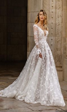 a woman in a white wedding dress standing on a stone floor