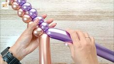 two hands are holding purple and pink balloons