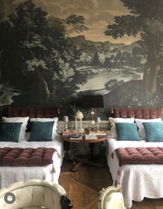 two beds sitting next to each other in front of a wall with a painting on it