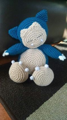 a crocheted blue and white stuffed animal sitting on top of a black rug