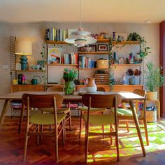 a dining room table and chairs with bookshelves in the background