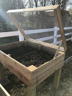 a wooden box filled with dirt next to a fence