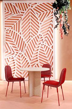 a table and chairs in front of a wall with an intricate cut out design on it