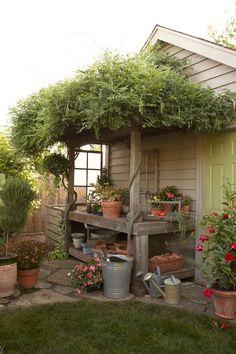 a garden shed with potted plants on the porch