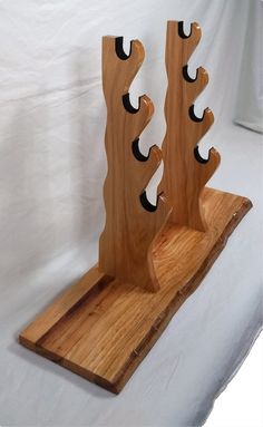 two wooden sculptures with holes in them sitting on a white sheeted surface and one is made out of wood