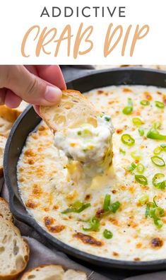 a hand dipping cheese into a skillet filled with crackers and green onions on top