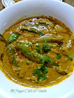 a white bowl filled with curry and green peppers