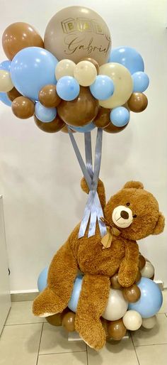 a brown teddy bear sitting on top of balloons