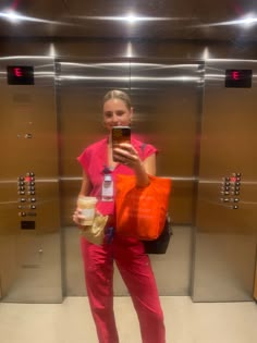 a woman taking a selfie in an elevator with her cell phone and orange bag