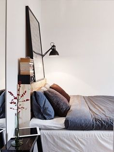 a bed sitting next to a lamp on top of a table