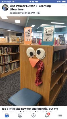 a paper turkey sitting on top of a book shelf next to a blue chair and bookshelves