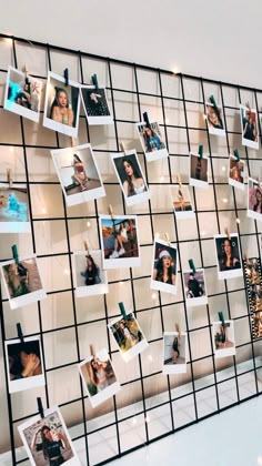 a wall with many pictures hanging on it's side and some lights in the background