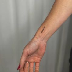 a woman's left hand with a small tattoo on the wrist and an arrow