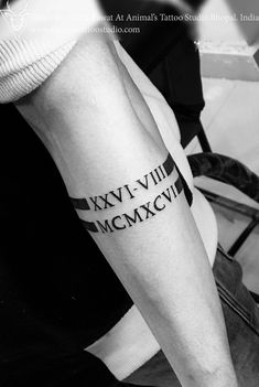 black and white photo of arm with roman numerals tattoo on man's leg