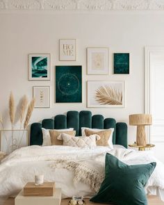 a bedroom with white walls, green headboard and pictures on the wall above it