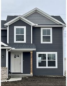 a gray house with white trim on the front door and windows, is shown in this photo