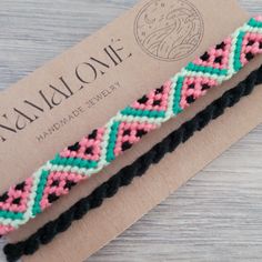 two braided bracelets sitting on top of a piece of paper next to a tag